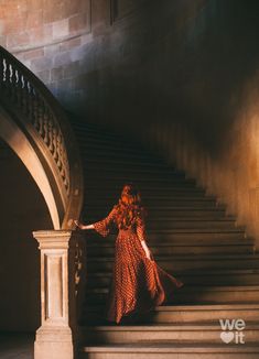 a woman in a red dress is standing on some stairs