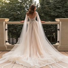 a woman in a wedding dress standing on a balcony with her back to the camera