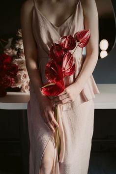 a woman in a pink dress holding a red flower