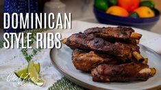 a plate with some meat on it next to a bowl of oranges and limes