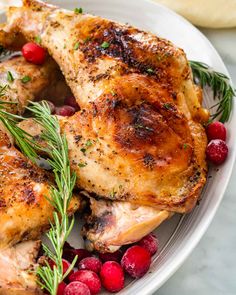 a white plate topped with chicken and cranberries on top of a marble counter