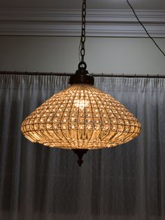 a chandelier hanging from the ceiling in front of a drapesed window