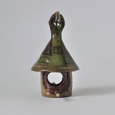 a ceramic birdhouse with a green roof