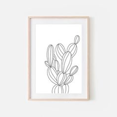 a black and white drawing of a cactus in a wooden frame on a plain wall