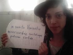 a woman holding up a sign that says in sancti vincentio miseridore contrive