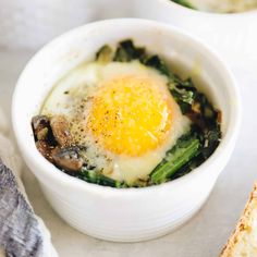 an egg in a bowl with mushrooms and bread on the side, ready to be eaten