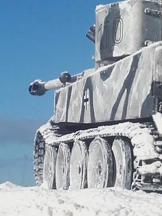 an old tank is covered in snow on a sunny day with blue skies behind it