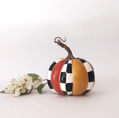 a decorative pumpkin sitting on top of a table next to a white and black flower