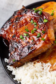 a black plate topped with meat and rice