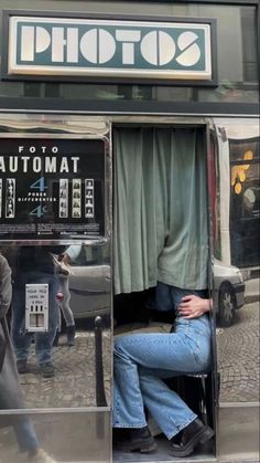 a man sitting in an atm machine on the side of the street with his head down