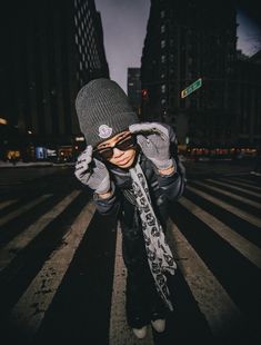 a person wearing a beanie and scarf is standing in the middle of a crosswalk