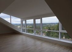 an empty room with wooden floors and large windows looking out onto the valley below it