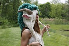 a woman wearing a crocheted mask with horns and dreadlocks on her head