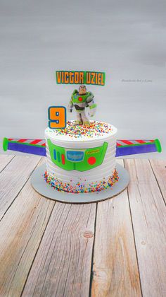 a birthday cake with sprinkles and a buzz lightyear figure on top