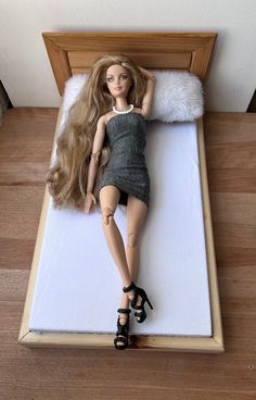 a doll laying on top of a bed next to a pillow