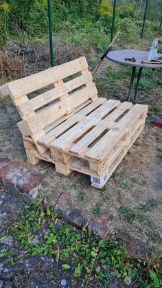 a bed made out of wooden pallets sitting on the ground next to a table