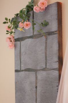 pink flowers are growing on the side of a brick wall in front of a window