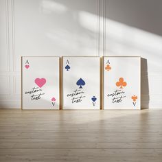 three cards with hearts and spades on them sitting in front of a white wall