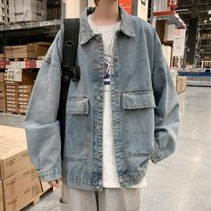 a man standing in a warehouse wearing a denim jacket