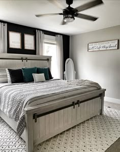 a bedroom with a bed, ceiling fan and pictures on the wall above it's headboard