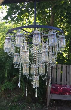 a chandelier made out of mason jars and hanging from a wooden bench in the garden