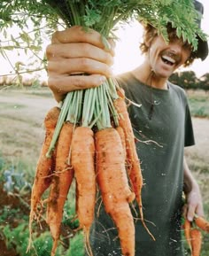 a man holding up some carrots in his hands