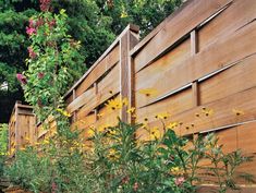 the fence is made of wood and has flowers growing on it