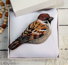 a bird sitting on top of a white pillow next to a beaded necklace and bracelet