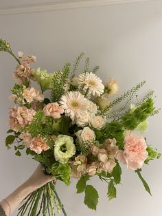 a bouquet of flowers sitting on top of a wooden table next to a white wall