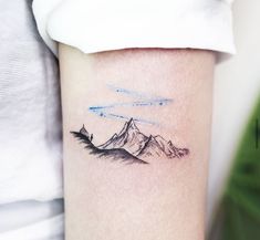 a tattoo on the arm of a woman with mountains and stars in the sky behind it