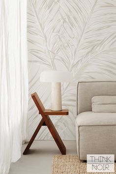 a chair and lamp in front of a wallpapered room with white drapes