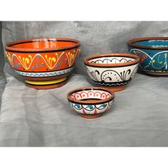 three bowls with designs painted on them are sitting side by side in front of a gray background