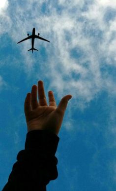 a person is reaching up to an airplane in the sky