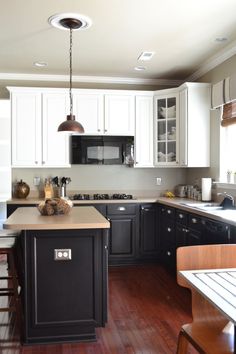 a kitchen with black and white cabinets, wood floors and an island in the middle