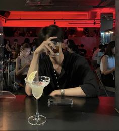 a woman sitting at a table with a drink in front of her