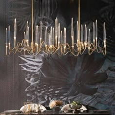 an elegant dining room with black walls and gold chandelier hanging from the ceiling