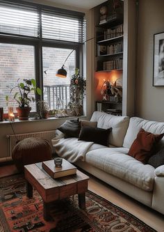 a living room filled with furniture next to a window covered in bookshelves and plants