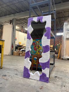 a large purple and white sculpture sitting inside of a room next to a painting easel