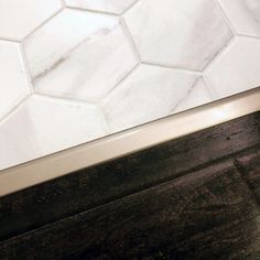 the corner of a bathroom with white tile and wood flooring, including a toilet seat