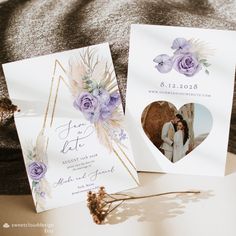 two wedding cards with purple flowers on them next to a bouquet of dried lavenders