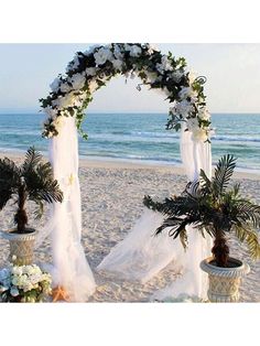 an outdoor wedding setup on the beach with palm trees and white flowers in vases