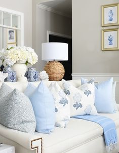 a living room filled with lots of white and blue pillows on top of a couch