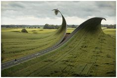 an artistic view of a curved road in the middle of a green field with trees