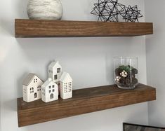 two wooden shelves with small houses on each shelf and a potted plant in the middle