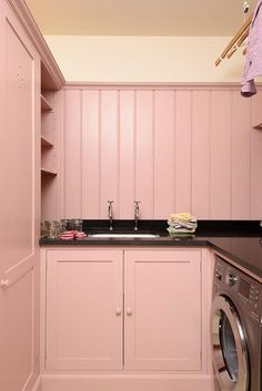 a laundry room with pink cabinets and a washer and dryer in the corner