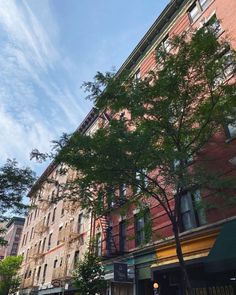 a tall brick building sitting on the corner of a street with lots of trees in front of it