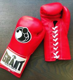 two red boxing gloves sitting on top of a wooden table