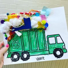 a child's hand holding up a drawing of a garbage truck with cotton balls