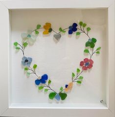 a heart made out of sea glass with flowers and leaves in the shape of a heart