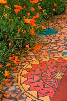 some orange flowers and green plants on the ground in front of a mosaic tile floor